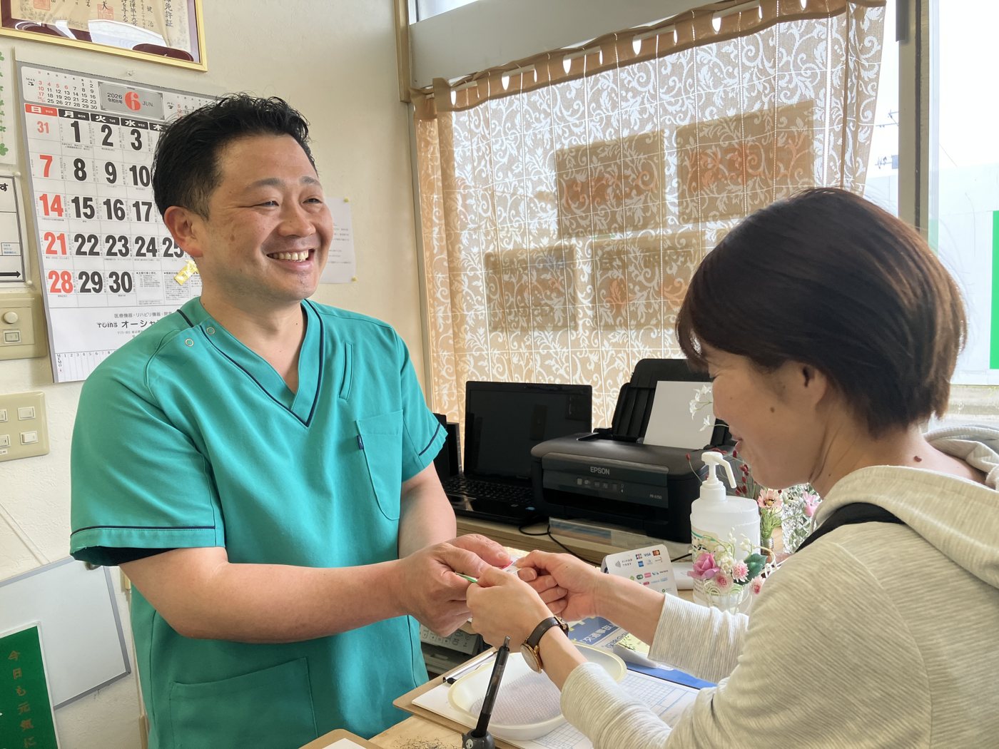 受付で患者さんをお迎えする院長 佐藤健治