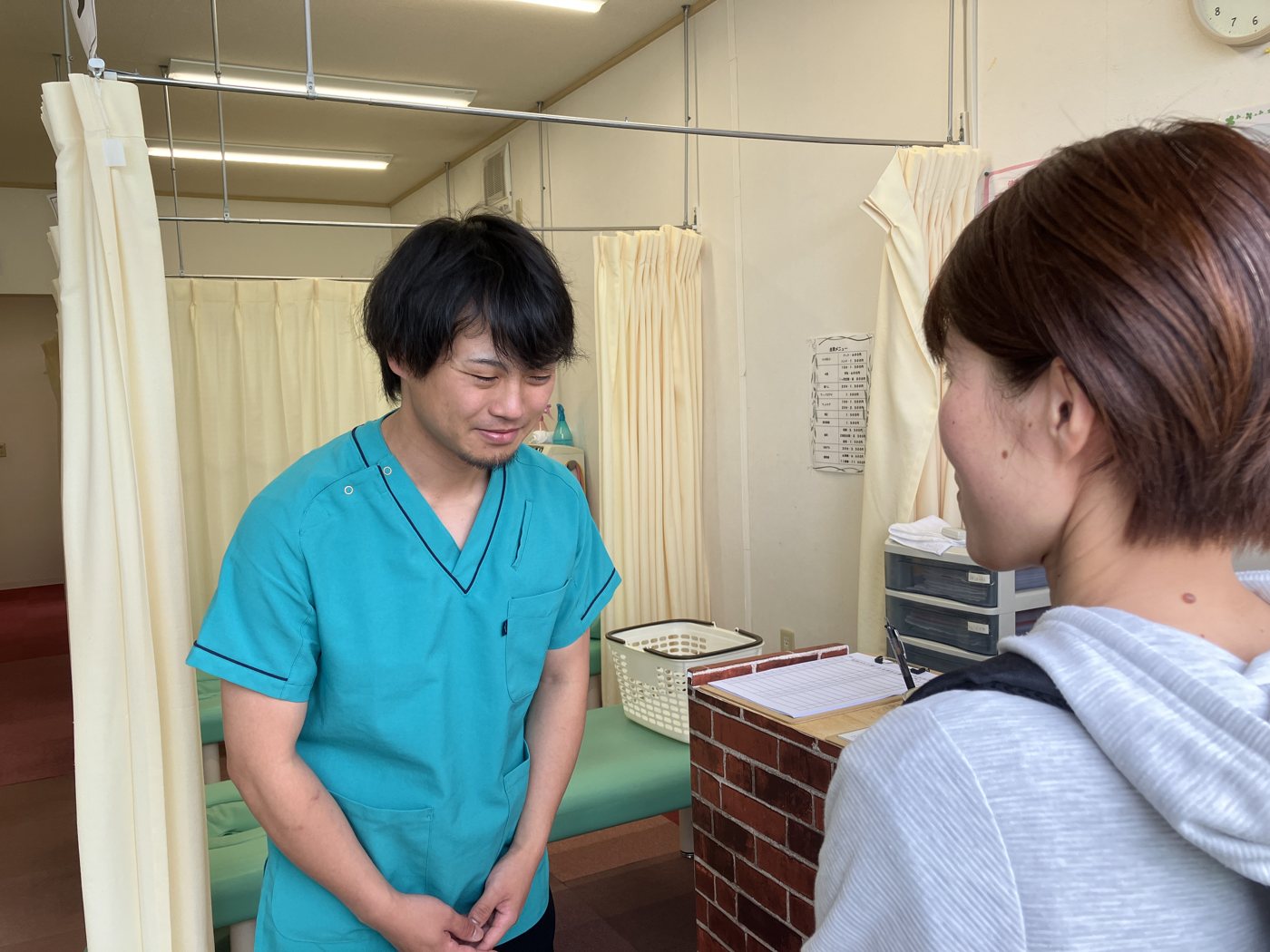 受付で患者さんをお迎えする佐藤信
